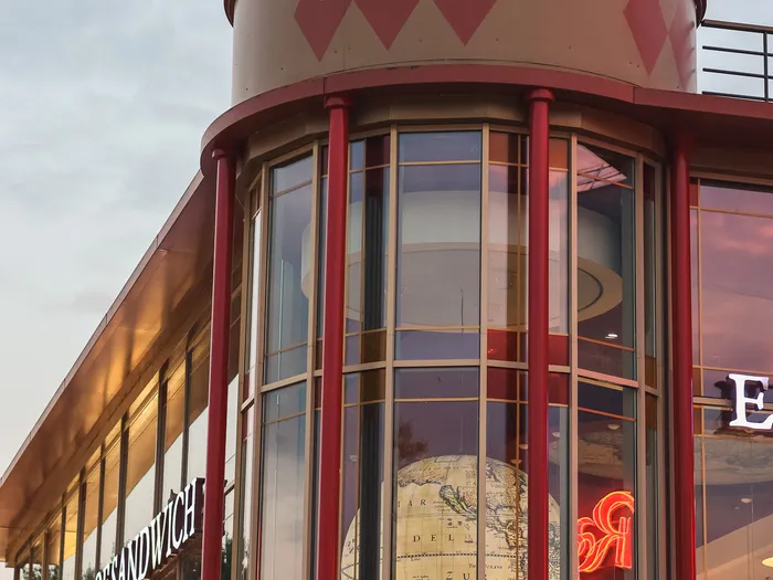 Façade vitrée et tour arrondie du restaurant Earl of Sandwich au crépuscule à Disney Village