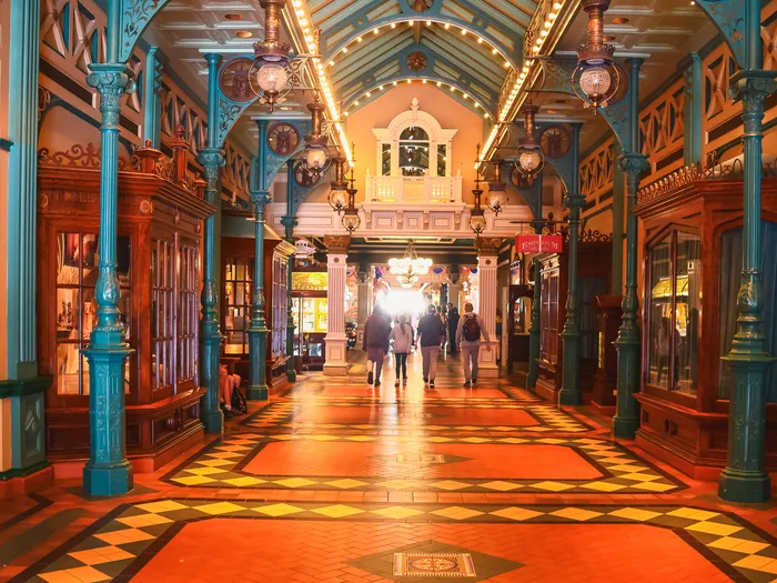 Longue galerie couverte du Liberty Arcade, colonnes turquoise, sol carrelé et vitrines de boutiques.