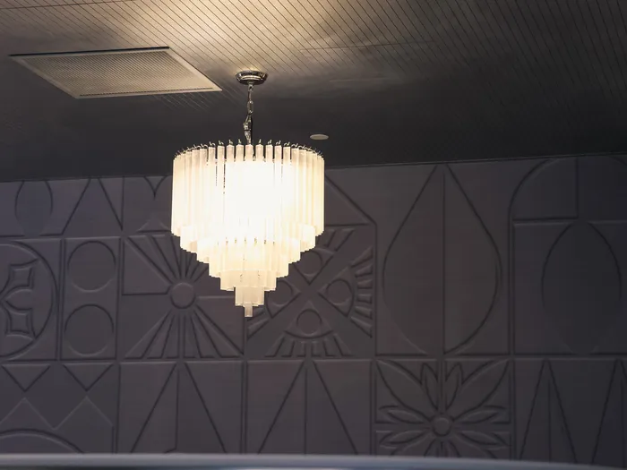 Crystal chandelier above a grey geometric-patterned wall, Disney Glamour shop at Disney Village