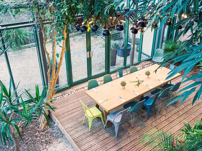 Verrière végétalisée de l’hôtel Val d’Europe avec grande table en bois et plantes tropicales