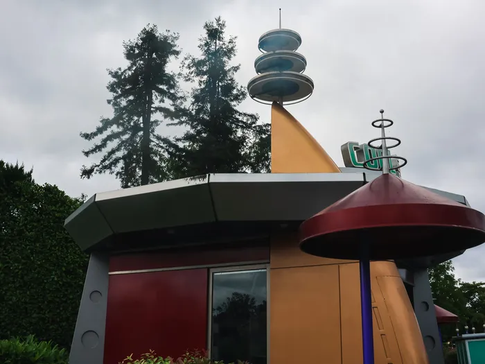 Toit en soucoupe rouge et antenne du kiosque Cool Station, dans le décor rétrofuturiste de Discoveryland.