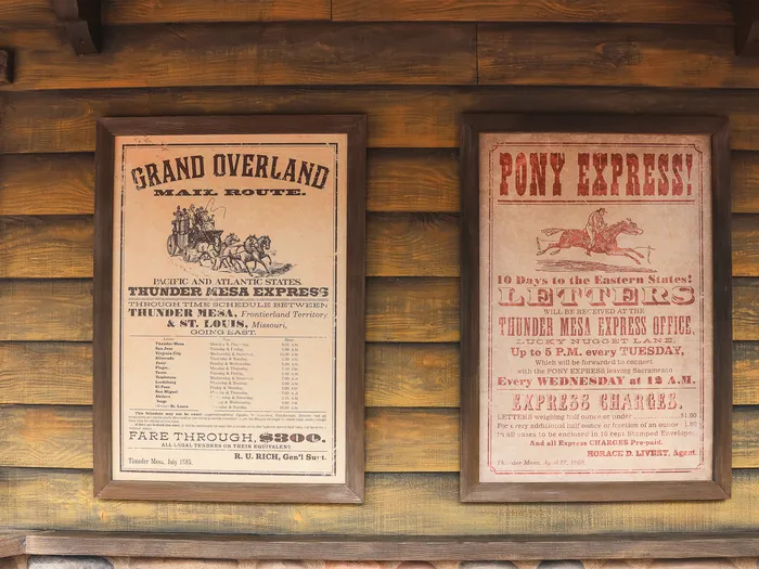 Deux affiches western encadrées, Grand Overland et Pony Express, sur mur en rondins à l’Overland Trail Cafe