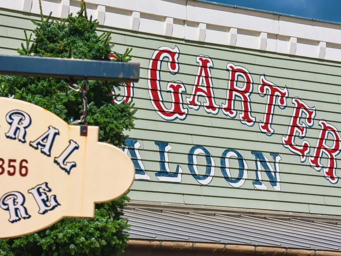 Façade en bois vert et enseignes Far West du Red Garter Saloon, décor western du Disney Hotel Cheyenne.