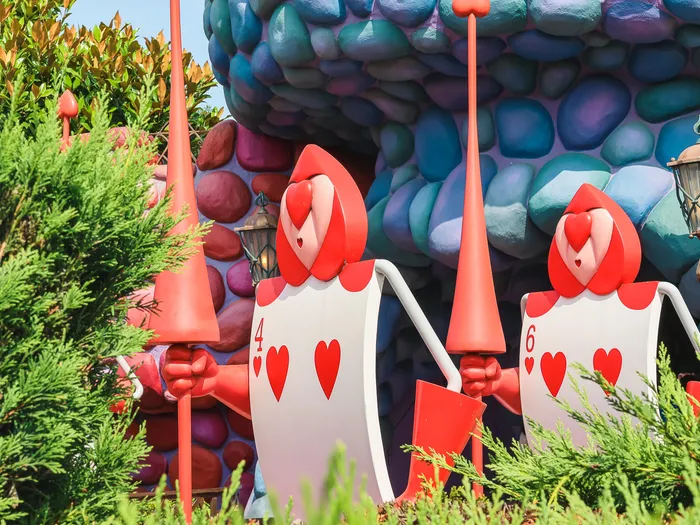 Deux cartes à jouer soldats, 4 et 6 de cœur, dans le décor de rocaille d’Alice’s Curious Labyrinth