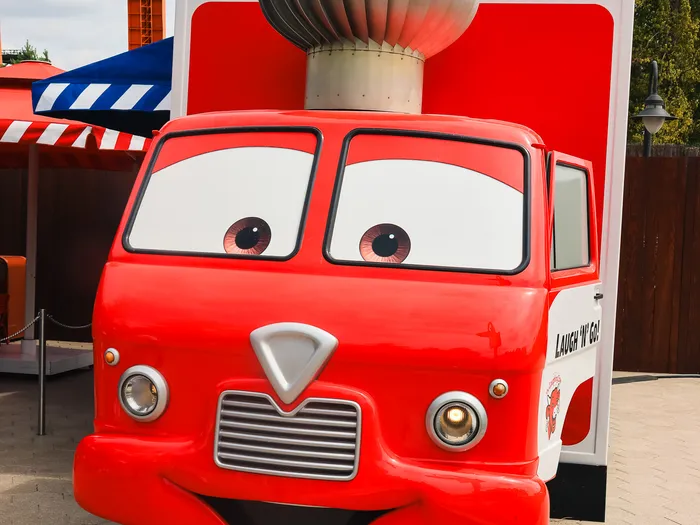 Kiosque Laugh ’N’ Go! en forme de camion rouge à visage animé façon Cars, vu de face en extérieur.