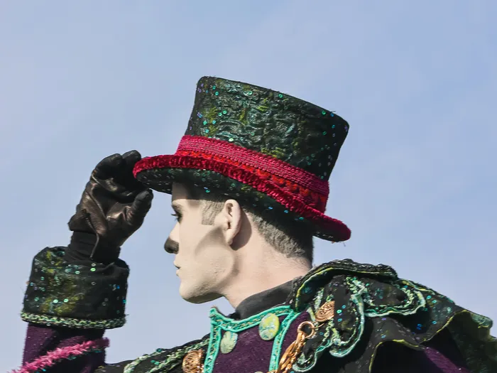 Artiste de profil en costume pailleté violet et vert coiffé d’un haut-de-forme, à la célébration Halloween du Parc Disneyland.