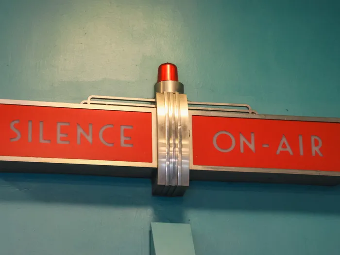 Panneau lumineux rouge Art déco « Silence On-Air » sur mur bleu, décor de studio de Stitch Live!