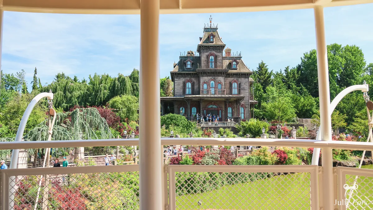 Phantom Manor on its hill, framed by the white posts of a boat at Thunder Mesa Riverboat Landing, in Frontierland at Disneyland Park