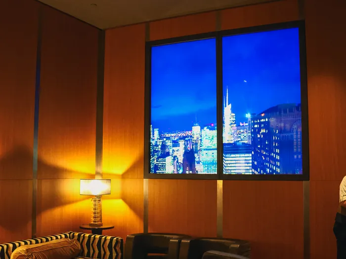 Coin salon du Skyline Bar avec canapé zébré, lampe d’appoint et baie éclairée sur la skyline de New York.