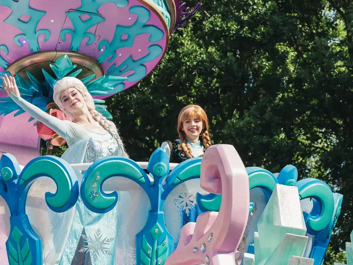 Les princesses Elsa et Anna saluant depuis le char glacé de La Reine des Neiges lors de Disney Stars on Parade.