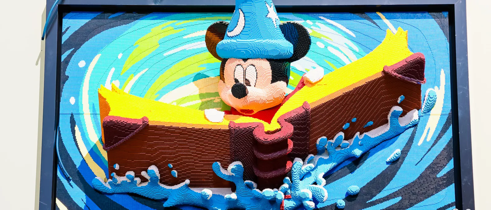 Sculpture en briques Lego de Mickey en apprenti sorcier, debout dans une barque parmi des vagues bleues, Disneyland Paris.