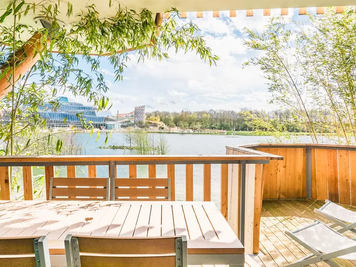Terrasse en bois avec table et transats face au lac et à l'Aqualagon, Villages Nature.
