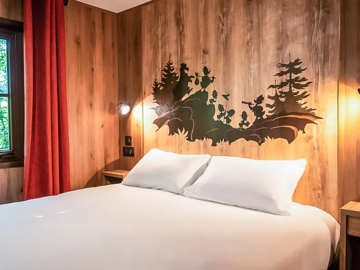 Lit double et fresque forêt sur mur en bois dans un bungalow du Davy Crockett Ranch.