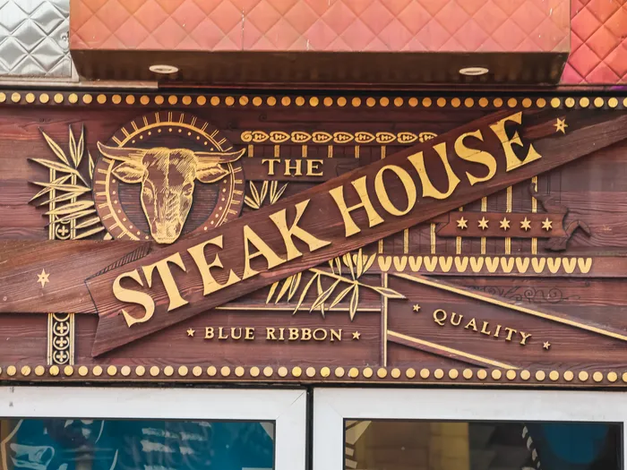 Enseigne en bois gravé du Steakhouse au Disney Village, avec tête de taureau dorée et mention Blue Ribbon Quality.