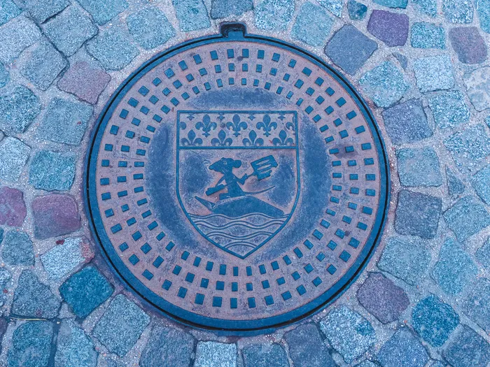 Plaque de fonte gravée des armoiries de Paris sur pavés, décor de l’attraction Ratatouille