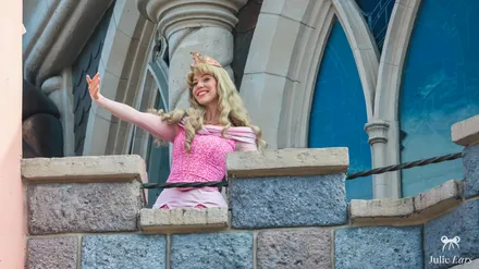 Princess Aurora waves from a castle balcony during World Princess Week at Disneyland Paris.