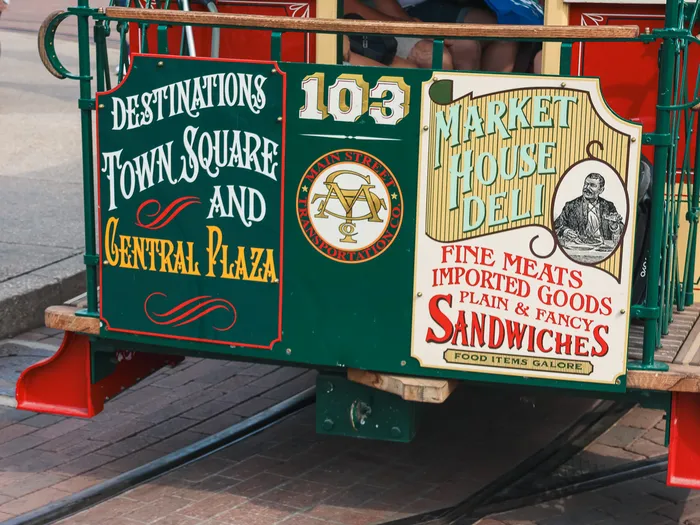 Panneaux peints du Horse-Drawn Streetcar 103 sur Main Street USA, mentionnant Town Square, Central Plaza et Market House Deli.