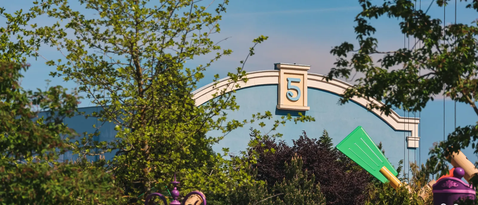Arche géante marquée d’un « 5 » et accessoires surdimensionnés de Toy Story Playland derrière la végétation, au Parc Disney Adventure World.