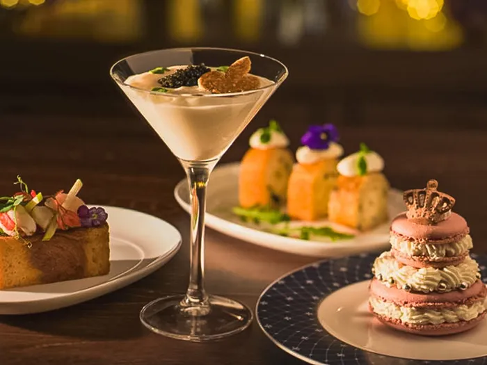 Canapé, cocktail au caviar, bouchées de saumon et macaron rose couronné servis au Fleur de Lys Bar