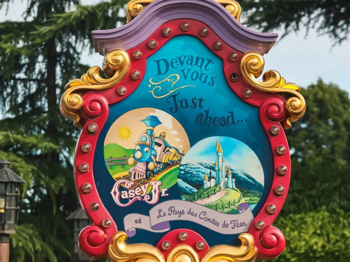 Entrance sign for Casey Jr. and Le Pays des Contes de Fées in Fantasyland, Disneyland Paris, in a red and gold frame with light bulbs