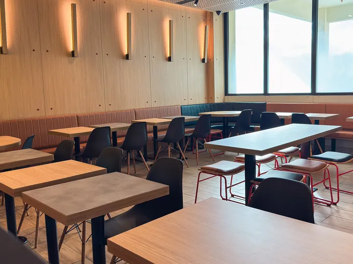 Salle du McDonald’s du Disney Village avec tables en bois, banquettes et appliques lumineuses