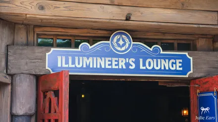 Blue and gold sign of the Illumineer’s Lounge, the Disney Lorcana space at Disneyland Paris, above a red wooden door