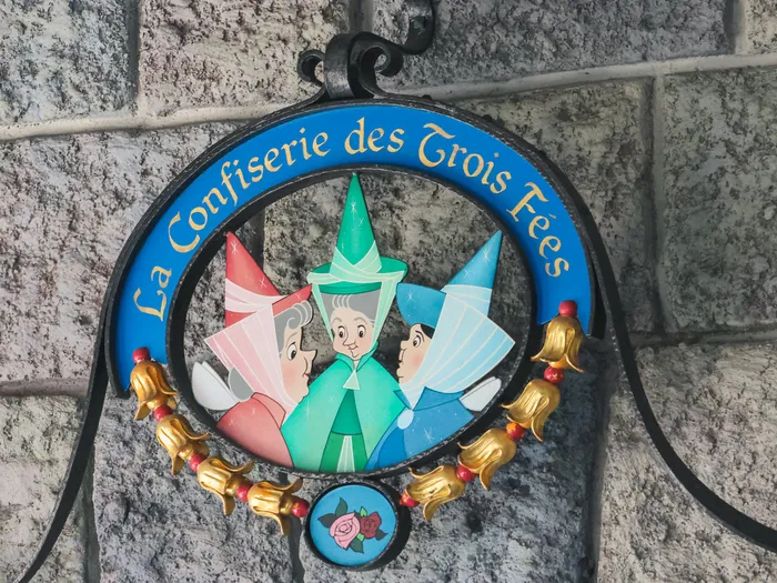 "La Confiserie des Trois Fées" sign featuring the three good fairies, at Disneyland Paris.