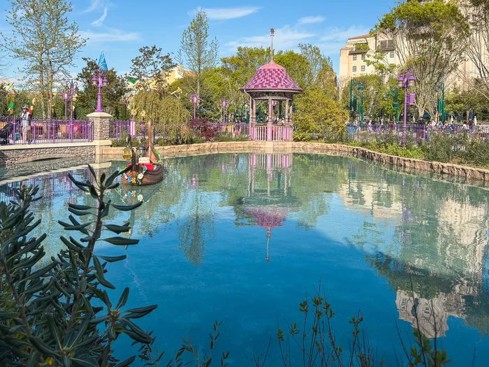 Vue large du lac avec kiosque rose et barque de l’attraction Raiponce Tangled Spin au Parc Disney Adventure World