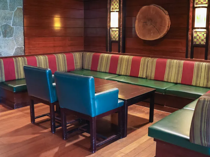 Coin banquette rayée rouge et vert avec fauteuils bleus au Redwood Bar du Sequoia Lodge, rondin de bois au mur