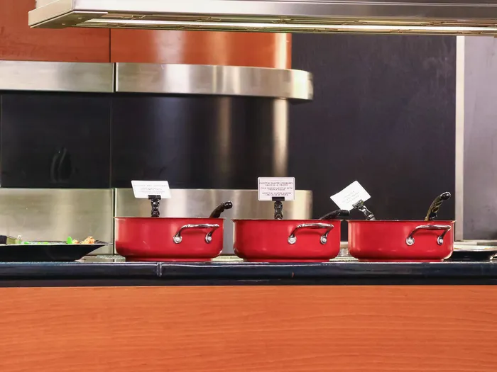 Trois casseroles rouges alignées sur le buffet chaud du Downtown Restaurant, devant le four Clay Oven