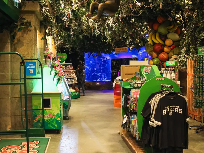 Aisle of the Boutique Rainforest Café with hanging foliage, an animatronic monkey and T-shirt displays