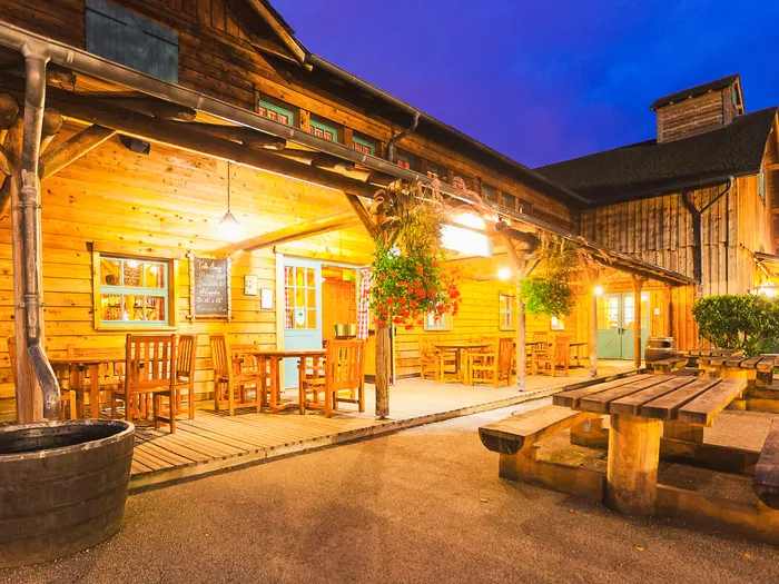 Bâtiment en bois de Crockett’s Saloon au crépuscule au Davy Crockett Ranch, terrasse éclairée et tables