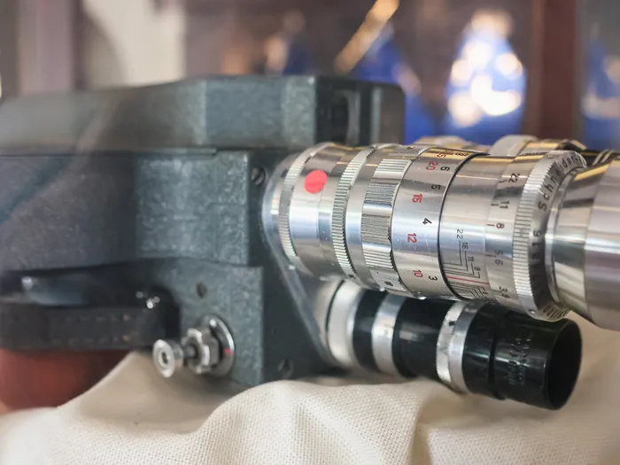 Old film camera with a Schneider lens displayed in a glass case at the Studio Photo photo spot
