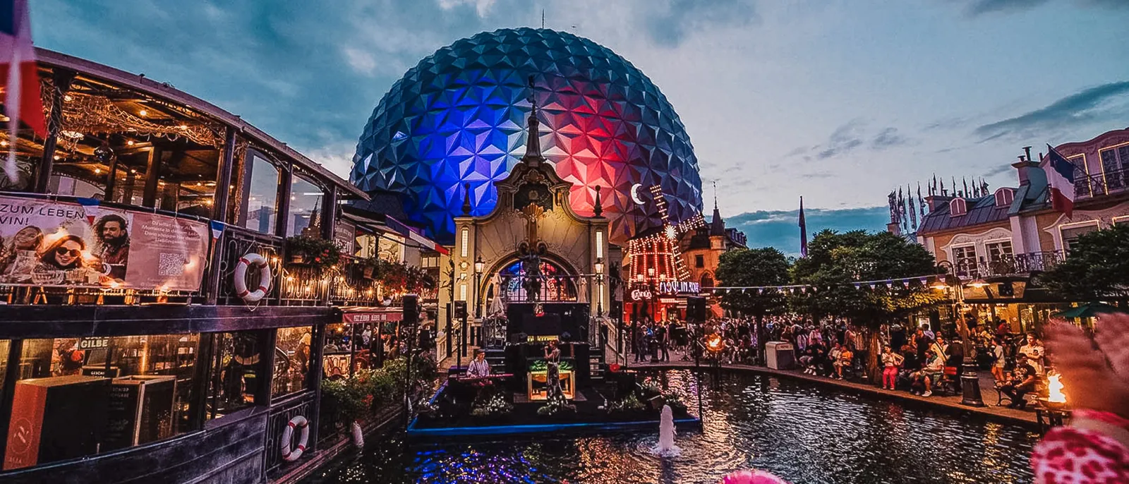 Grand dôme argenté illuminé de bleu et rouge au bord de l’eau, le soir à Europa-Park