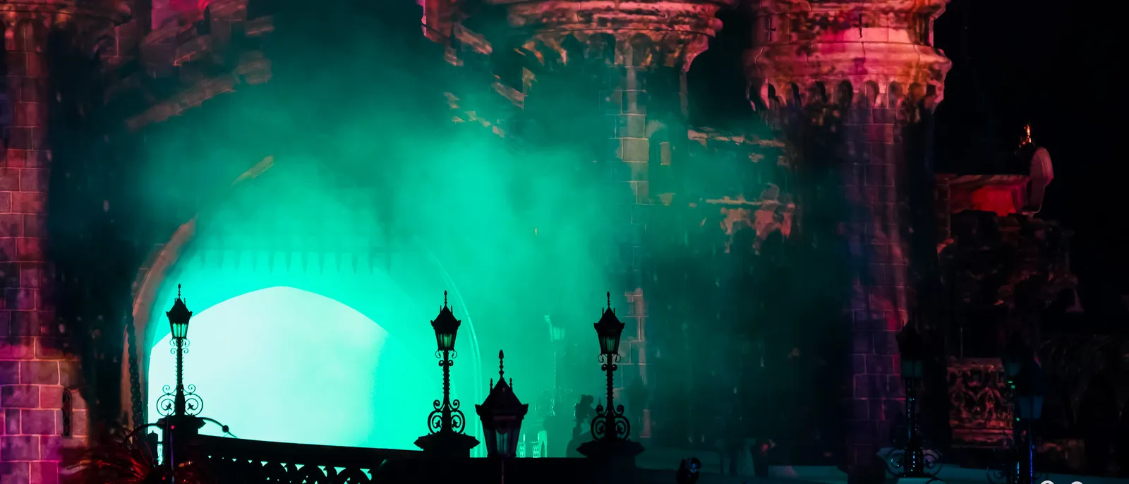 Château de la Belle au Bois Dormant baigné de brume verte et de lumières rouges lors d’un spectacle Halloween nocturne.