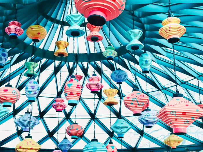 Lanternes en papier multicolores suspendues à la verrière bleue de l’attraction Mad Hatter’s Tea Cups à Fantasyland.