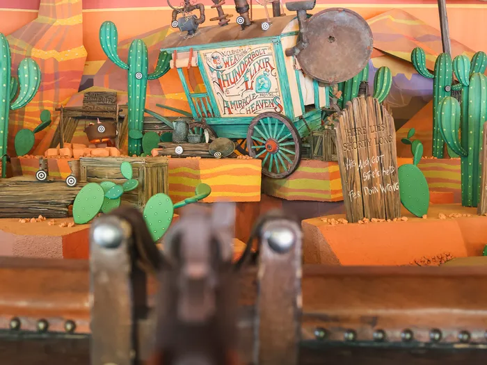 Décor de désert avec chariot, cactus et cibles vu depuis une carabine du Rustler Roundup Shootin’ Gallery.