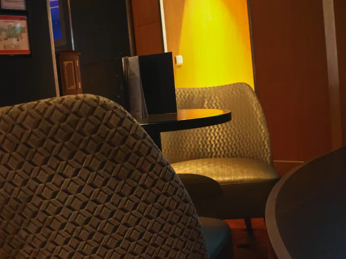 Fauteuils texturés et petite table autour d’une niche à lumière dorée dans le salon du Skyline Bar.