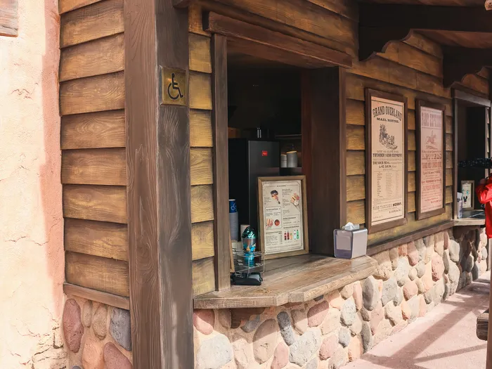 Comptoir de commande en angle, murs en bois et soubassement de galets à l’Overland Trail Cafe, Frontierland