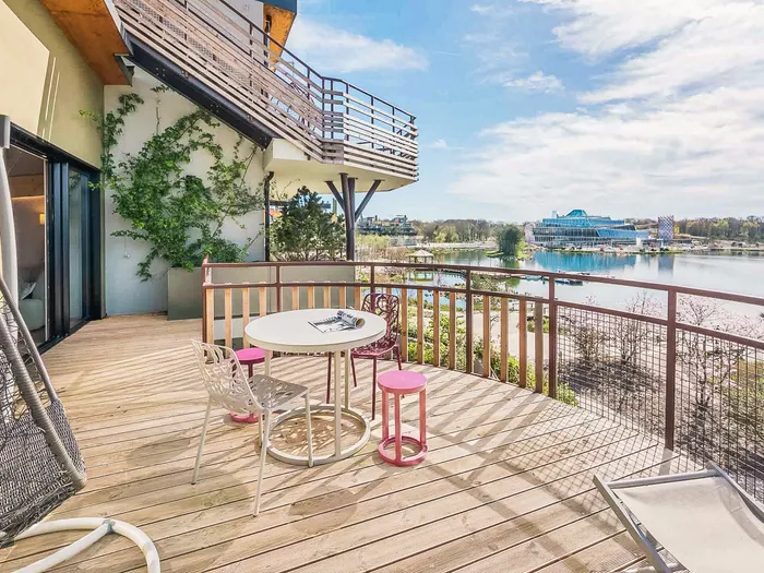 Terrasse d’appartement du Village Nature avec fauteuil suspendu, table et vue sur le lac