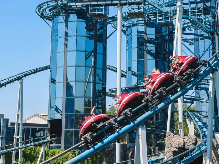 Wagons rouges de l’Euro-Mir sur les rails bleus devant ses tours miroir à Europa-Park