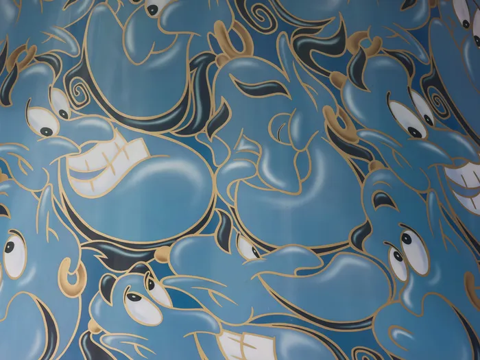 Colonne peinte d’une multitude de visages du Génie bleu, décor de l’attraction Les Tapis Volants