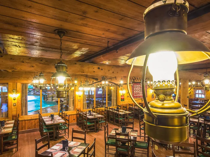 Salle à manger boisée du Crockett’s Tavern avec une grande lanterne en cuivre et des tables dressées