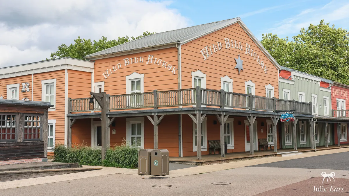 Orange wooden "Wild Bill Hickok" facade of Disney Hotel Cheyenne at Disneyland Paris, with a sheriff’s star and a wooden balcony gallery