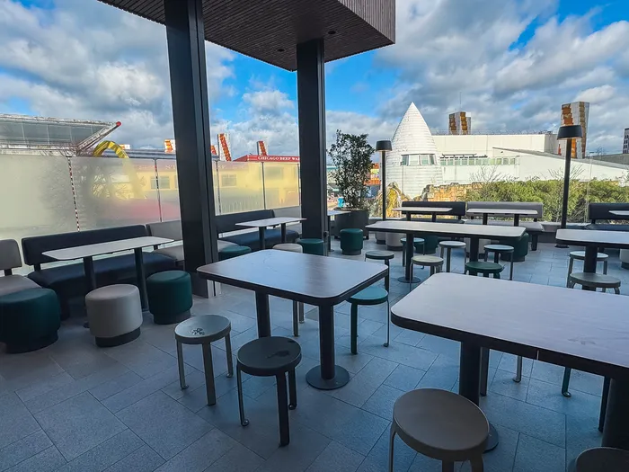Terrasse en hauteur du McDonald’s avec tables et tabourets, ouverte sur le Disney Village