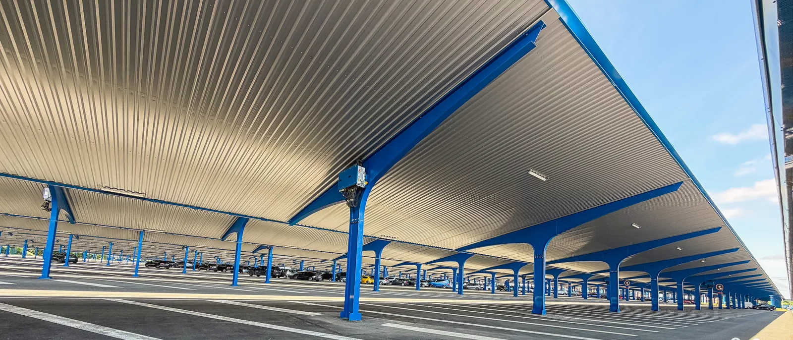 Parking visiteurs de Disneyland Paris avec ses ombrières bleues et sa toiture métallique au-dessus des voitures