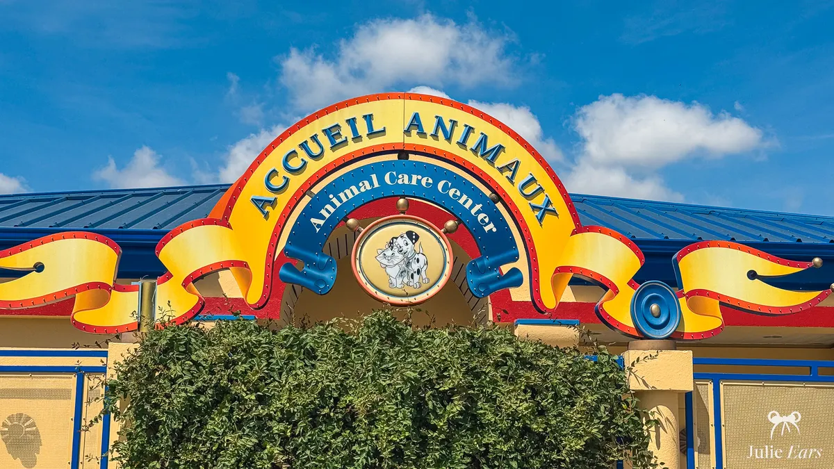 Yellow, red and blue "Animal Care Center" sign at Disneyland Paris, with a medallion of Disney animals including a Dalmatian puppy