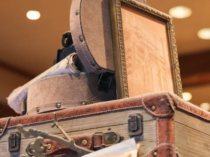 Old brown leather suitcase topped with a grey felt hatbox and a gold frame showing the Hollywood Tower Hotel, at Disneyland Paris.