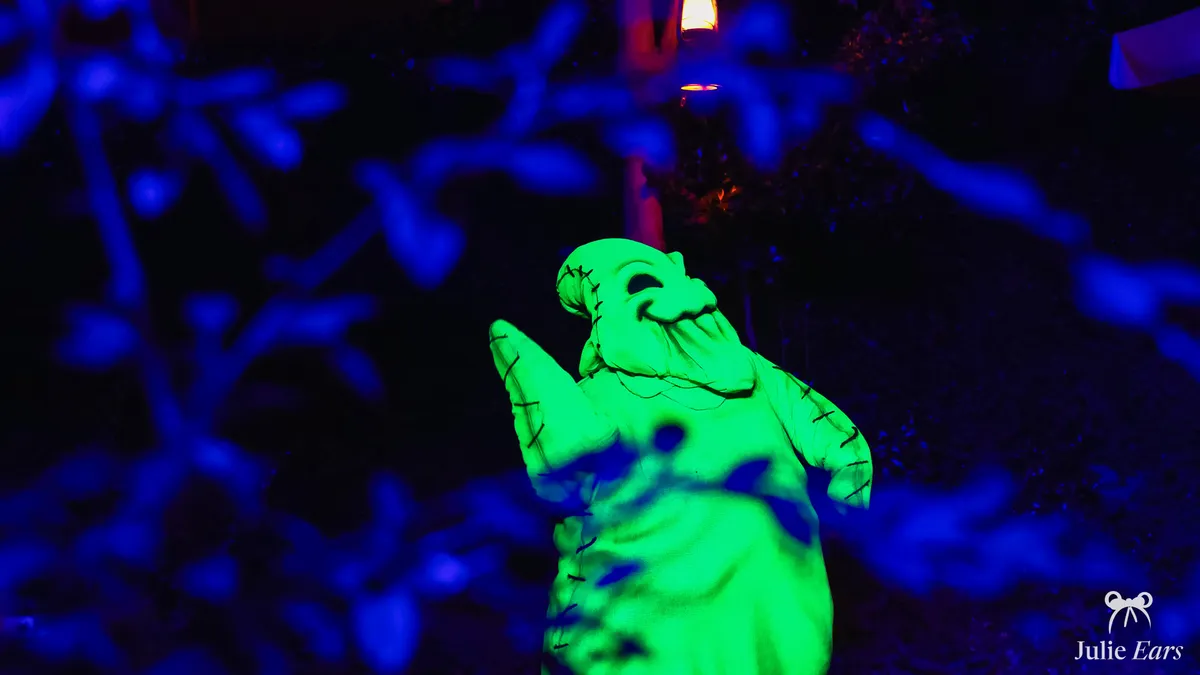 The silhouette of Oogie Boogie, lit in green at night, among the Halloween decorations at Disneyland Paris.