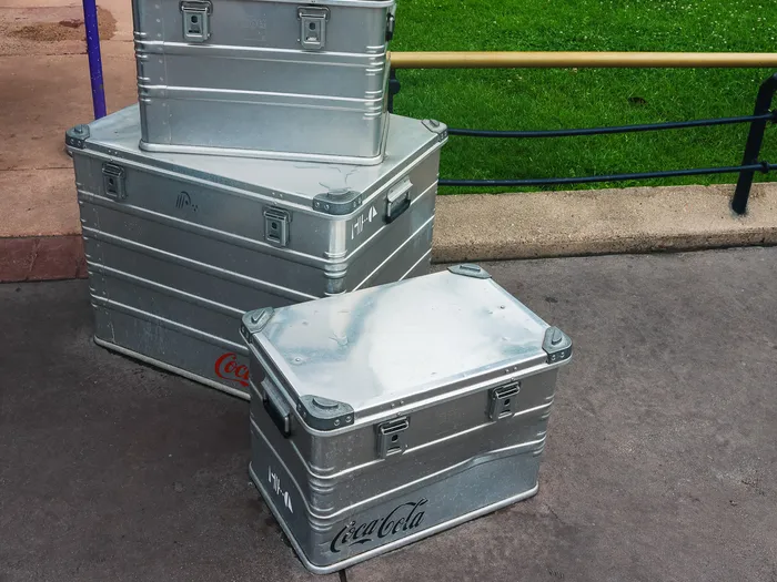 Caisses en aluminium siglées Coca-Cola posées à l’extérieur du kiosque Cool Station, à Discoveryland.